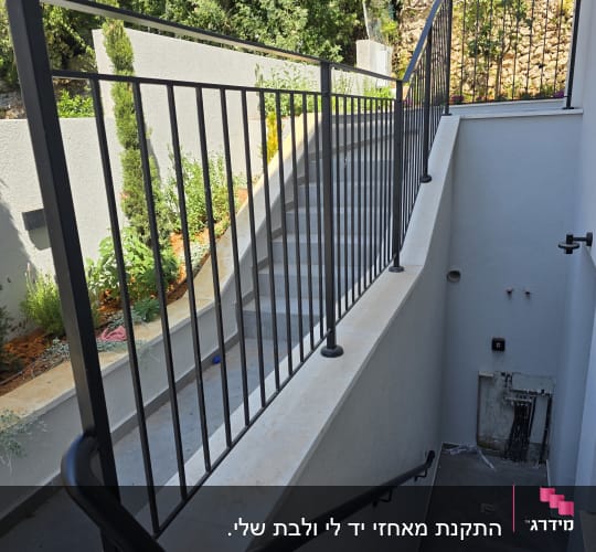 מעקה מתכת על מדרגות חיצוניות עם צמחייה מסביב